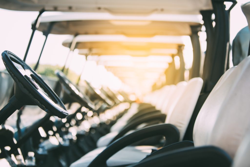 row of golf carts on a golf course. golf course carts cars at luxury resort sport venue in neat line row.