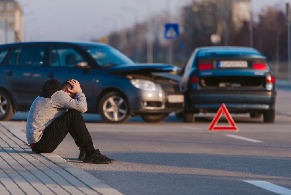 A man is looking sad after two cars crashing on the road
